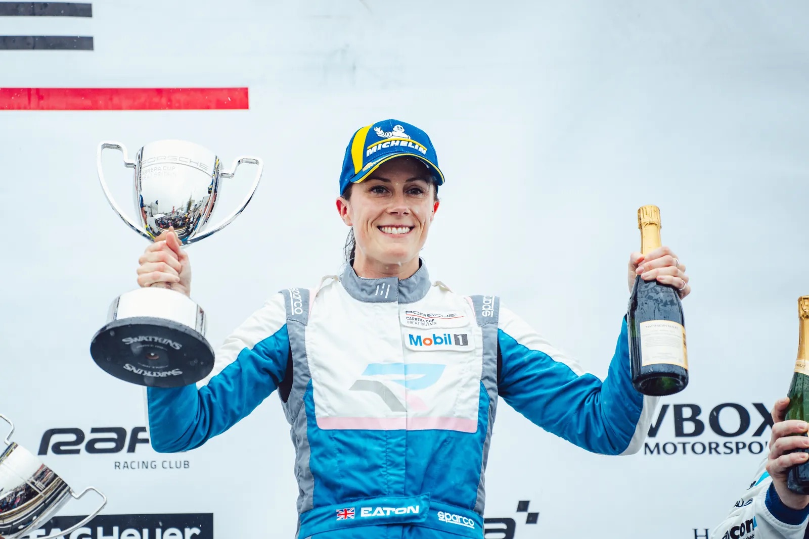 Abbie Eaton on the podium with a trophy and champagne