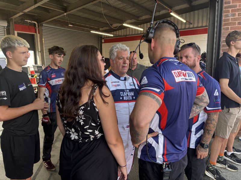 George Grant and the team crew talking in the pit lane