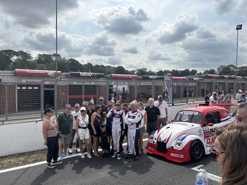 The team and guests posing with Car 146 in the pit lane